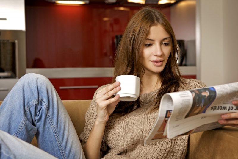 robo advisor new - woman reading paper drinking coffee